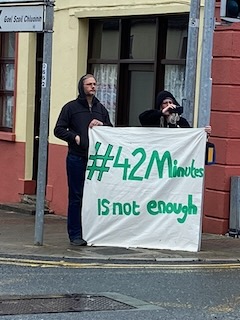 42 minutes is not Enough Two people standing on a street corner holding a sign that reads '#42 Minutes IS not Enough'
