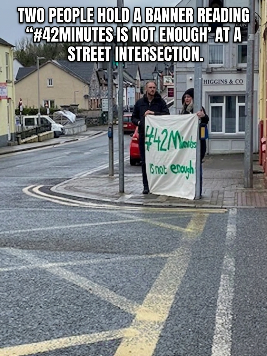 42 minutes is not enough Banner with Sligo DPO Two people stand at a street intersection holding a banner reading '#42Minutes Is not enough'